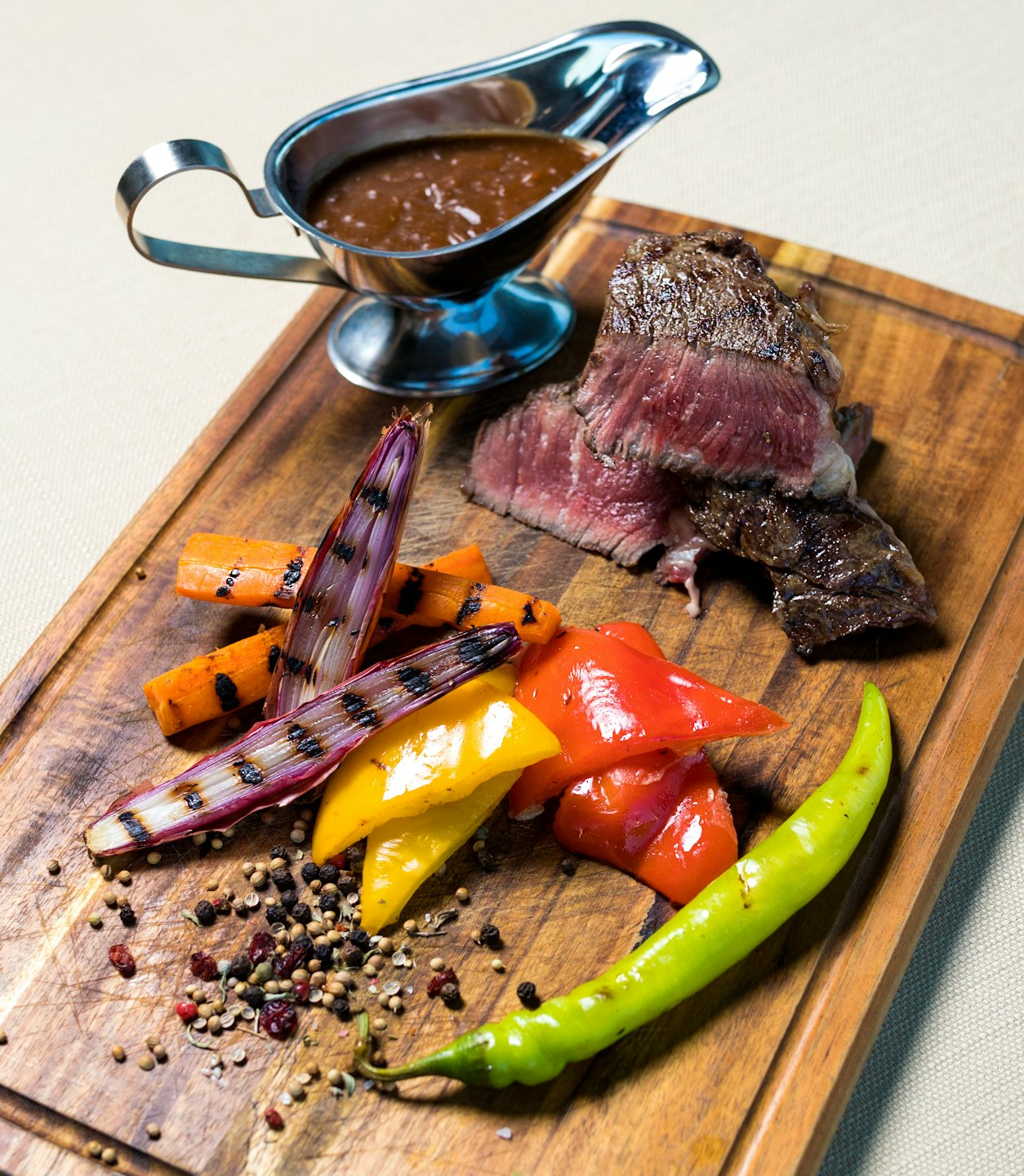 Bistecca succosa al sangue con verdure arrosto su tagliere di legno.